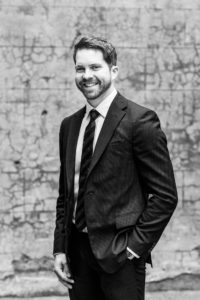 Black and white business portrait in front of a concrete wall