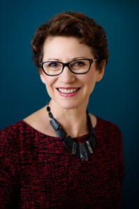 Business portrait of woman in glasses against blue background